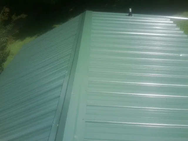 New green metal panels meeting at the ridge of a roof — Flat Roof Repair work by our crew in Murrells Inlet