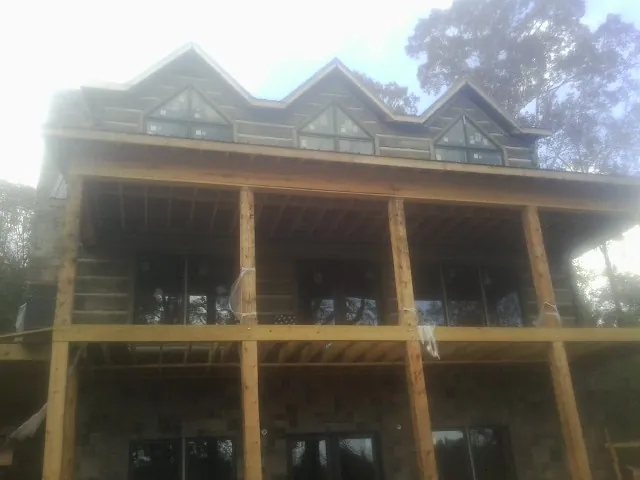 Dormers and porch framing on a large log home under construction — Roof Coating work by our crew in Murrells Inlet