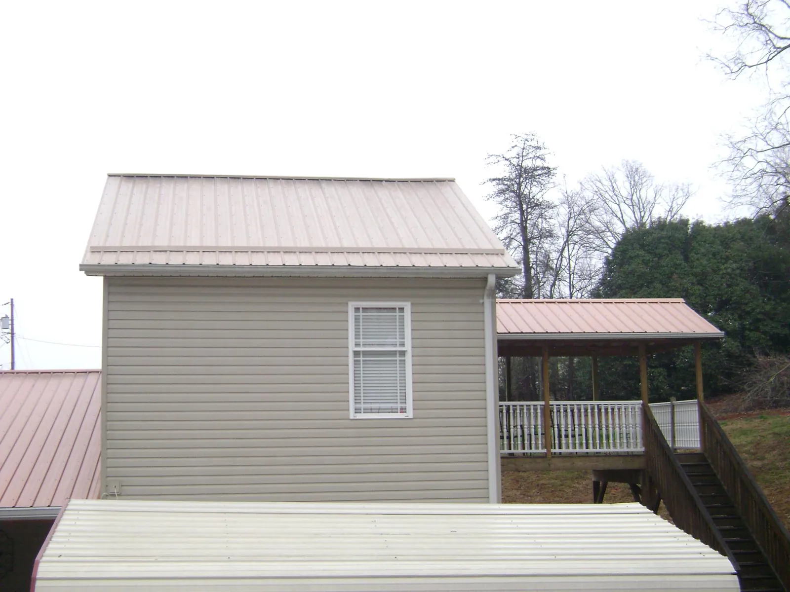 Tan metal roofs on a two story addition and attached porch, from a Roof Replacement job in Murrells Inlet