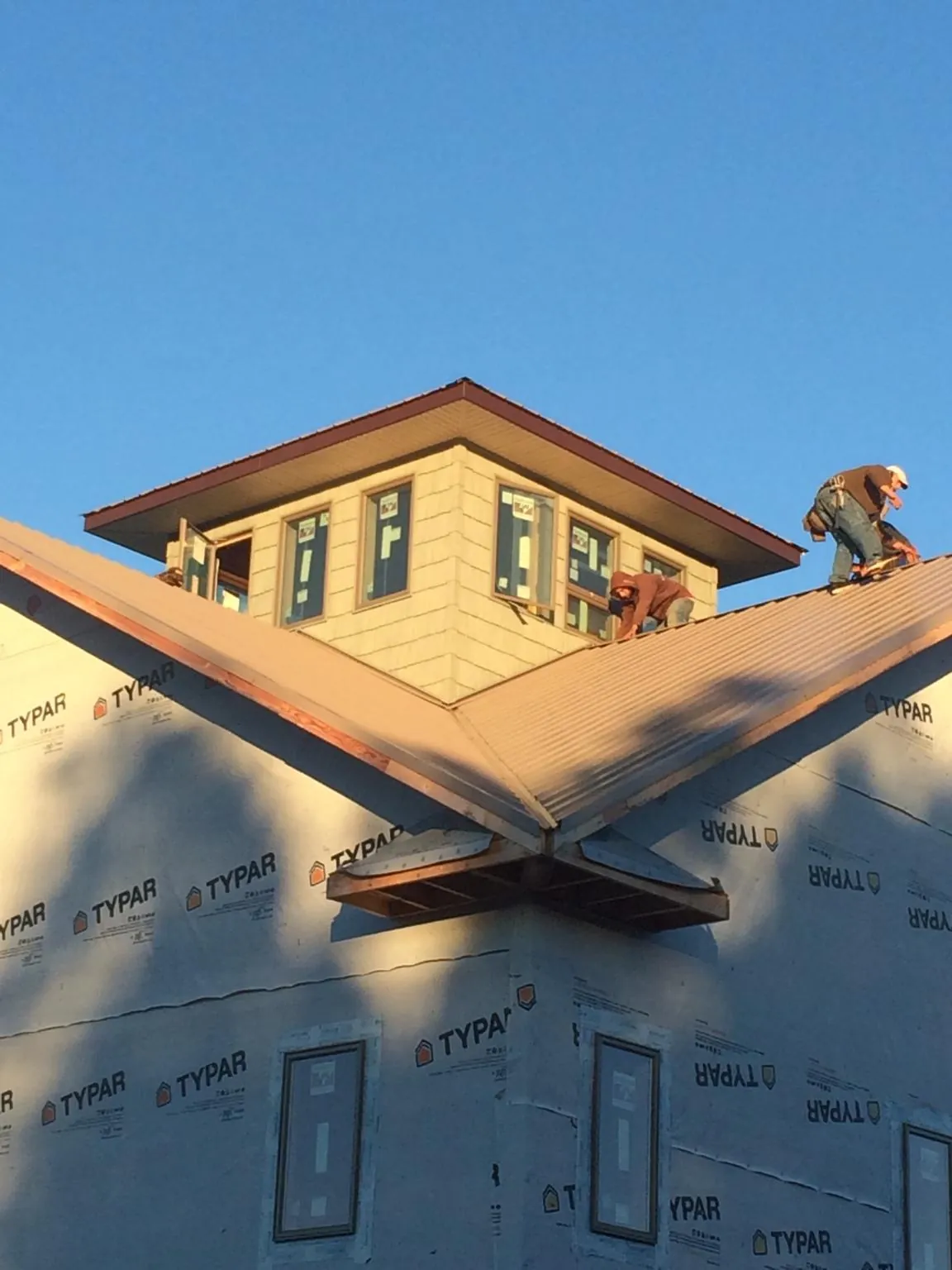 Roofers working around a rooftop cupola on a new metal roof at sunset — Roof Waterproofing in Murrells Inlet by Roofing Brothers